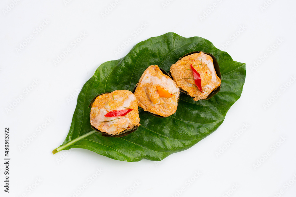 Thai streamed fish curry in banana leaves on noni or morinda citrifolia leaves on white background.