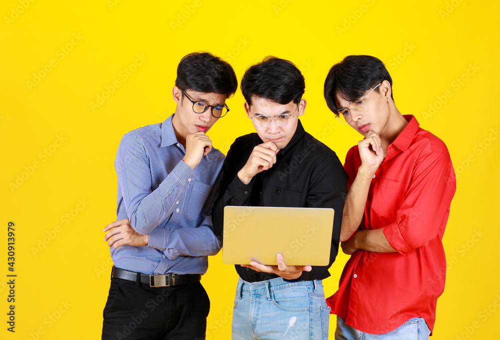 Portrait 3 adults asian men and 1 of them hold laptop on hand. All of them wearing eyeglass and look at laptop while feel intened with something on laptop. In concept Brainstorm of Teamwork Portrait 3 adults asian men and 1 of them hold laptop on hand. All of them wearing eyeglass and look at laptop while feel intened with something on laptop. In concept Brainstorm of Teamwork