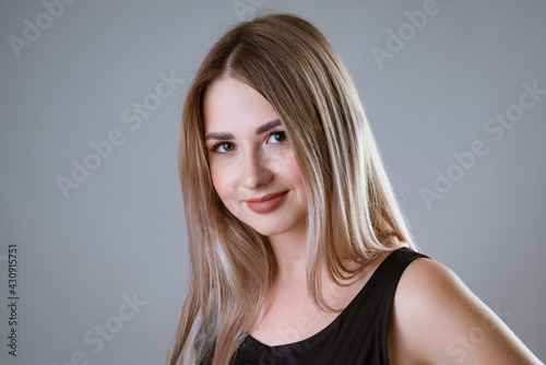portrait of a young happy caucasian girl in a black t-shirt posing on a light background