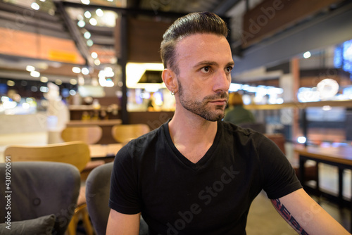 Portrait of handsome man sitting at coffee shop while thinking