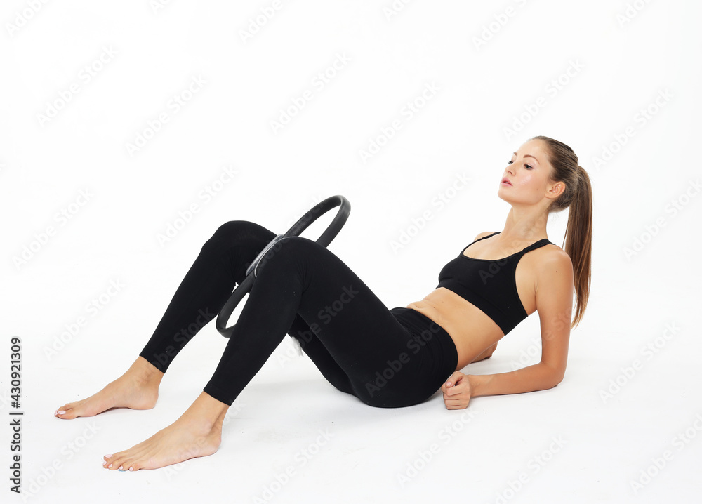 Young sporty woman with perfect body sitting on the floor and having a training with pilates ring