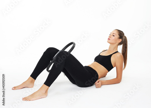 Young sporty woman with perfect body sitting on the floor and having a training with pilates ring