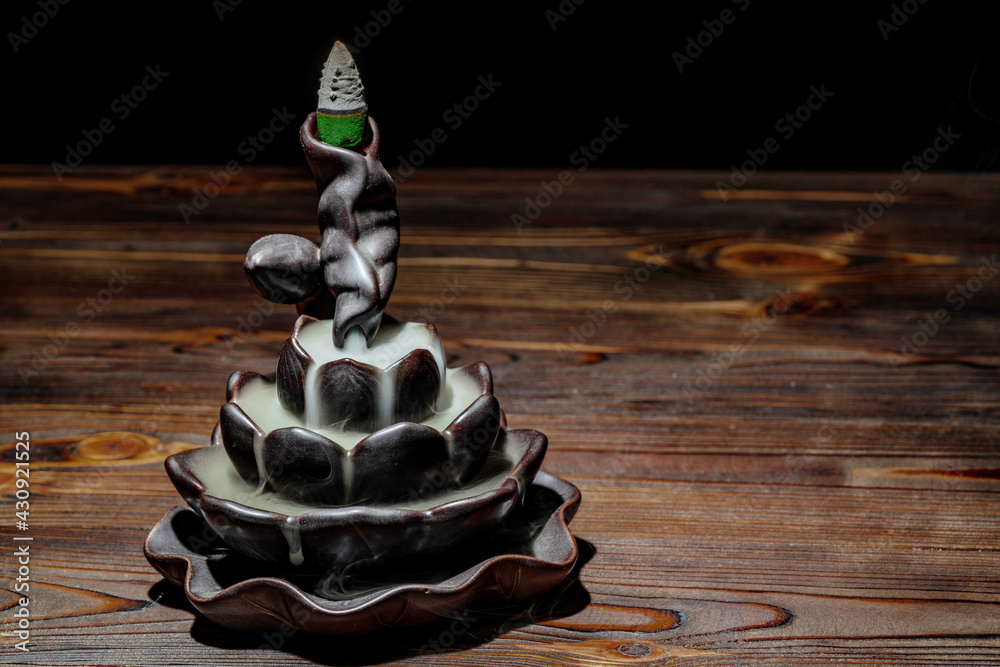 Ceramic backflow incense burner in the form of lotus flower. Incense cones holder. Dark mystic concept. - obrazy, fototapety, plakaty 