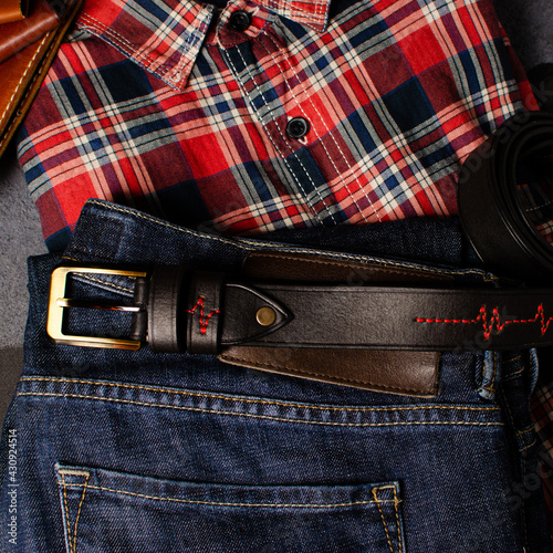 a plaid shirt, jeans and a belt are on the table. Vintage style of clothing