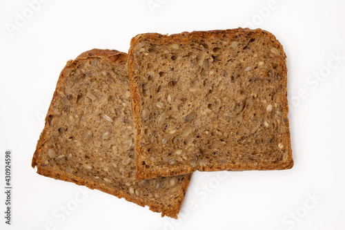 Two slices of wholegrain bread with seeds of sunflower, flax, and sesame. Healthy vegetarian food. Isolated flatlay.