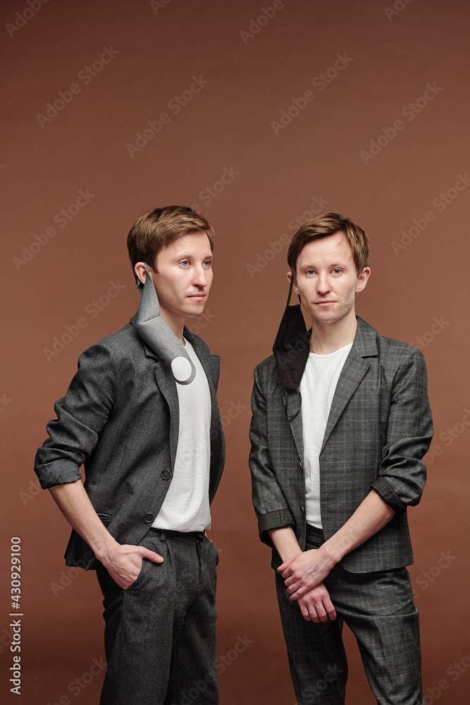 Confident young twins with masks hanging on ears Confident young twins with masks hanging on ears