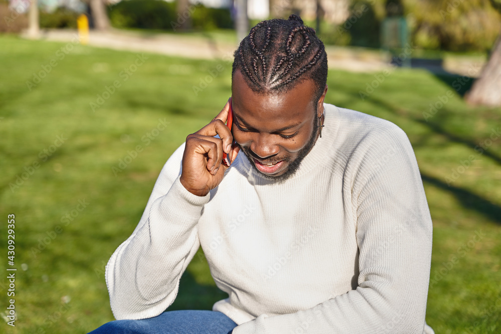 Happy black man talking on smart phone sitting in a park on a sunny day. Happy black man talking on smart phone sitting in a park on a sunny day.