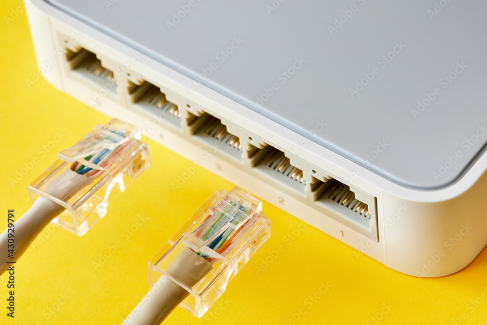 Ethernet cables connected to Desktop Switch or routerboard on a yellow background. Close-up, selective focus Ethernet cables connected to Desktop Switch or routerboard on a yellow background. Close-up, selective focus