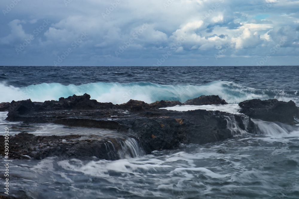 Big wave behind rocks in the ocean in Qawra. Malta on a cloudy day.