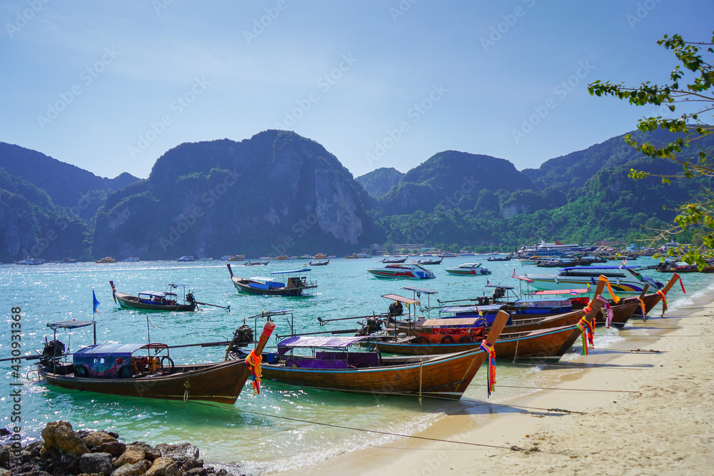 Obraz premium Old Thai wooden boats. Traditional tropical seascape. Traditional wooden longtail taxi boat. Fishing boat docked off the coast of the blue sea.