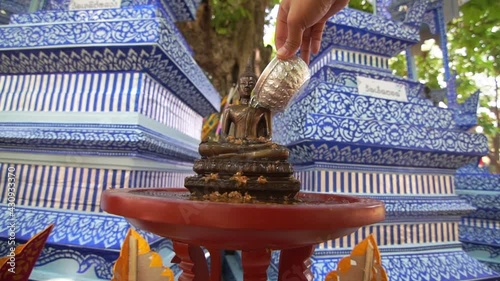 Close up Face of Buddha statue with Hand of sprinkle water onto a Buddha image.
Songkran the most famous festival of Thailand