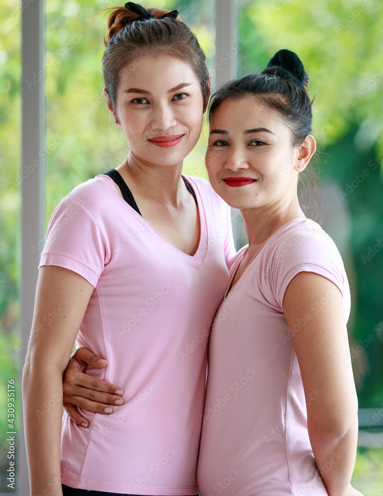 Close up Asian beautiful sportive healthy women with hair tied wearing pink sport shirt and black elastic pants, doing exercise or yoga, stretching body and making meditation in indoor gym or home. Close up Asian beautiful sportive healthy women with hair tied wearing pink sport shirt and black elastic pants, doing exercise or yoga, stretching body and making meditation in indoor gym or home.