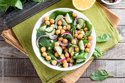 Spinach, cucumber, chickpeas, onions and lemon salad on a light table. Top view