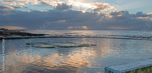 Sunrise reflection on resting rock in Dale Brook Tide Pool in Cape Town South Africa SA photo