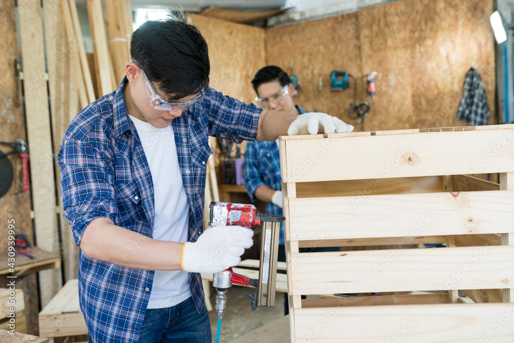 Carpenter hammering nails into wood with a automatic nailer. Carpenter worker with machine at wood workshop. Carpenter hammering nails into wood with a automatic nailer. Carpenter worker with machine at wood workshop.