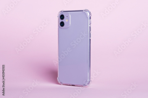 Phone case mock up side view. Purple smart phone in clear silicone case isolated on pink background, rotated position. Smartphone perspective view