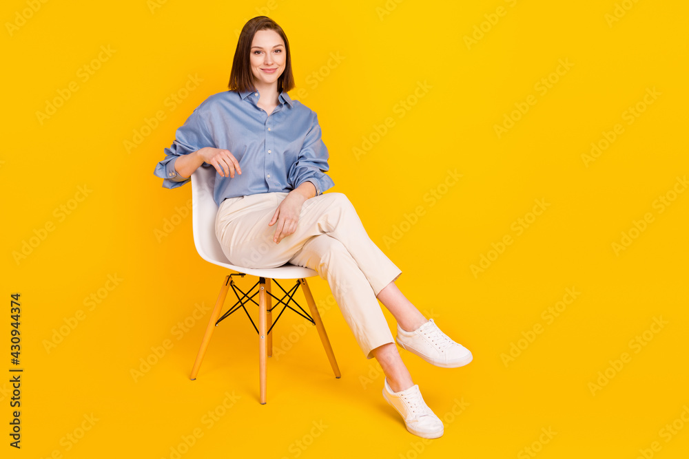 Portrait of attractive content cheerful girl executive manager sitting on office chair isolated over vibrant yellow color background Portrait of attractive content cheerful girl executive manager sitting on office chair isolated over vibrant yellow color background