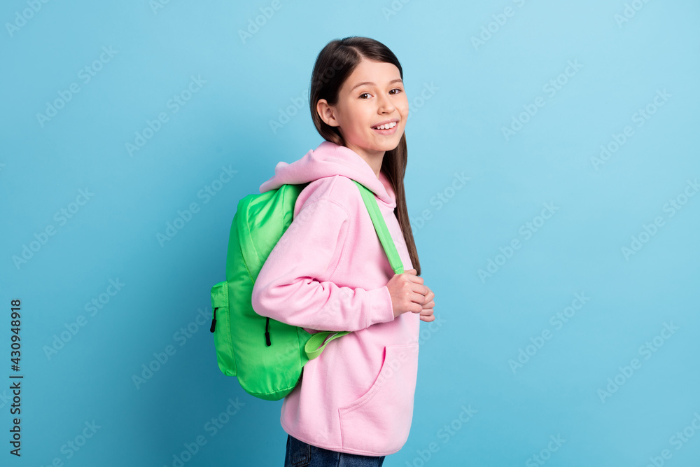 Profile side photo of young preteen girl happy positive smile pupil wear backpack isolated over blue color background Profile side photo of young preteen girl happy positive smile pupil wear backpack isolated over blue color background