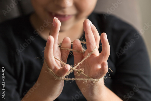Close-up of child's hands playing a traditional homemade rope game. Conceptual of lifestyle