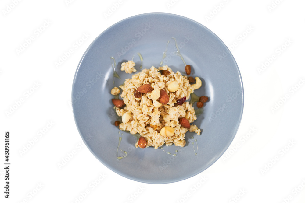 Top view of tasty and appetizing oatmeal with dried fruits and raisins,nuts on white background. Concept of delicious and healthy porridge for maintain body weight or emaciation. Top view of tasty and appetizing oatmeal with dried fruits and raisins,nuts on white background. Concept of delicious and healthy porridge for maintain body weight or emaciation.