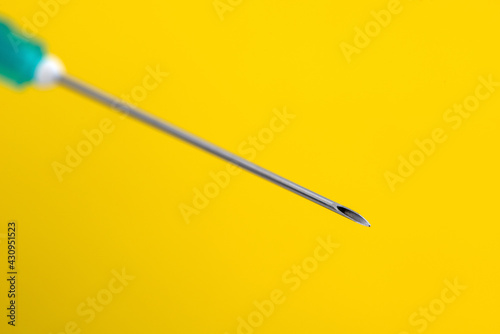 Medical syringe needle on a yellow background.