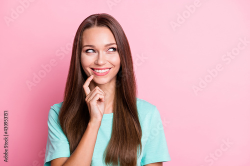 Portrait of young happy smiling cheerful woman looking copyspace thinking hold finger on chin isolated on pink color background