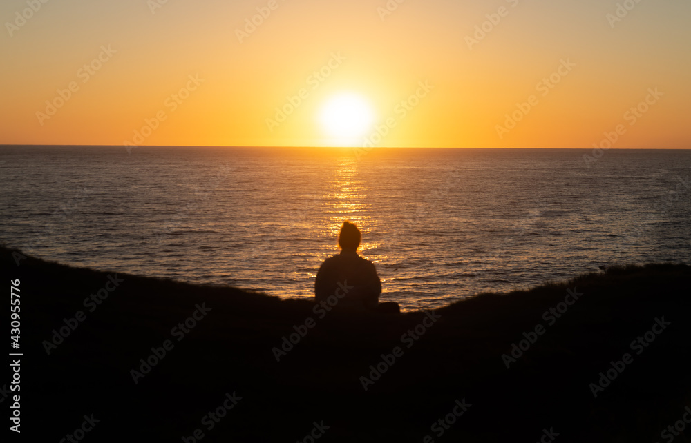 Rear View of Woman Silhouette Sitting in the Edge of a Hill Watching the Sunrise