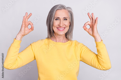 Photo of happy cheerful good mood mature woman showing okay sign wear yellow sweater isolated on grey color background