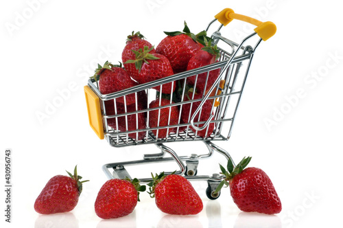Concept d'achat de fraises avec un chariot de supermarché en gros plan sur fond blanc