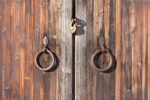 Fotografie Fragment of an old wooden gate with a wrought iron handle with rust stains