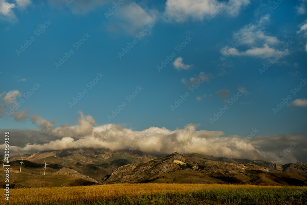 View of the mountains with clouds and wind turbines on the hills. View of the mountains with clouds and wind turbines on the hills.