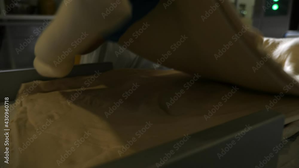 Large dough layer is placed on a pile of sheetsby a worker in a bakery plant Large dough layer is placed on a pile of sheetsby a worker in a bakery plant