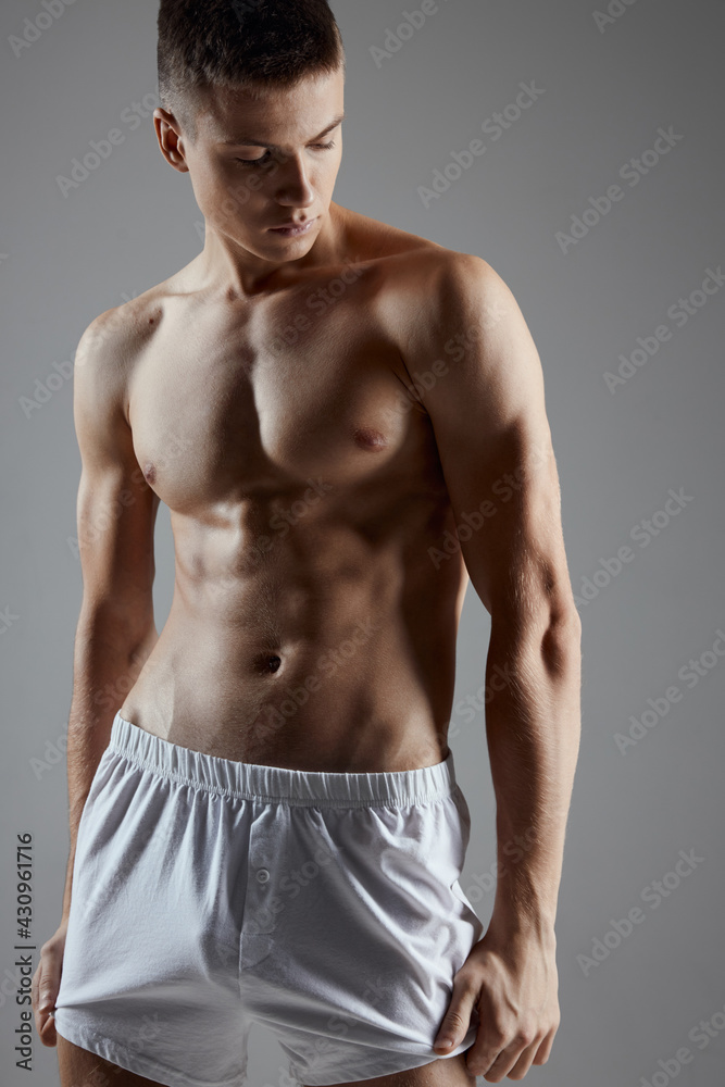 athlete with a pumped-up torso in white shorts on a gray background