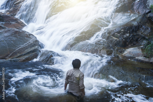 A man looking at pure tropical waterfall.