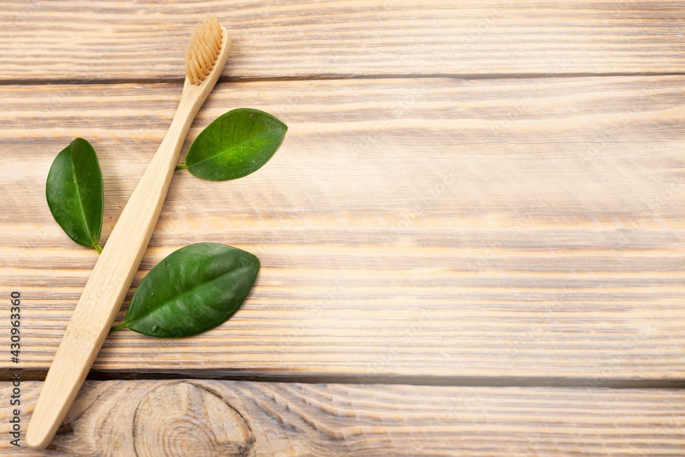 Natural eco friendly bamboo toothbrush with green tree leaves on a wooden background. Choose a wooden toothbrush. Recycling concept, no waste, no plastic, top view Natural eco friendly bamboo toothbrush with green tree leaves on a wooden background. Choose a wooden toothbrush. Recycling concept, no waste, no plastic, top view