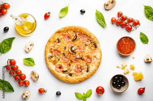 Tasty mushrooms and ham pizza and cooking ingredients tomatoes and basil on white background. Top view
