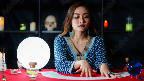 Foto Asian fortune teller reading cards with closed eyes