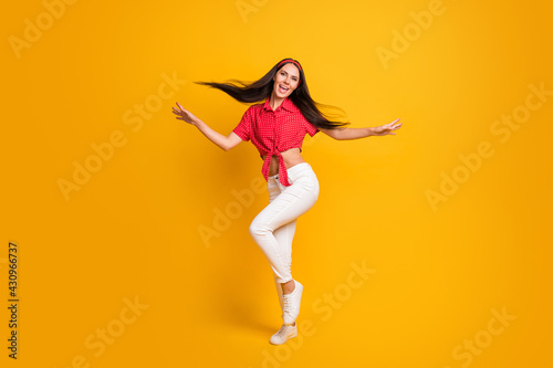 Full length photo of sweet cute young lady wear red shirt dancing hands arms sides isolated yellow color background
