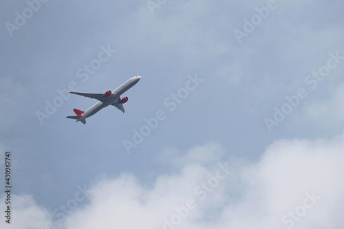 Airplane flying in the blue sky with white clouds. Passenger plane at flight close up, travel concept