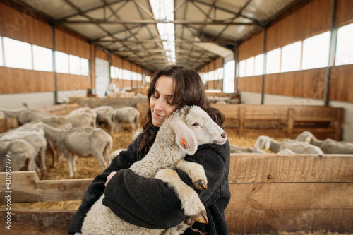 Εκτύπωση καμβά young happy woman on a sheep farm hugging with sheep