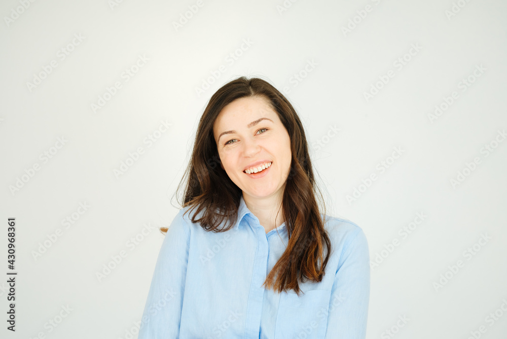 Young brunette in blue shirt smiles and is very happy. Woman laughs and exudes happiness. copy space for text Young brunette in blue shirt smiles and is very happy. Woman laughs and exudes happiness. copy space for text