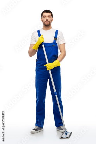 profession, service and people - male worker or cleaner in overal and gloves cleaning floor with mop over white background