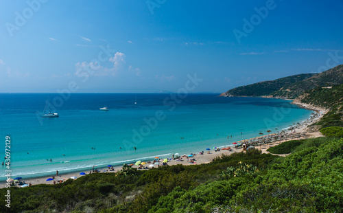 crowded beach in the summer. Small Bay with yachts and crysral clear water.
