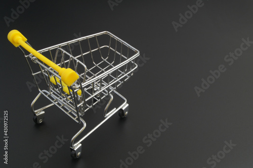 Shopping cart on black background with space for text, buy and sale concept