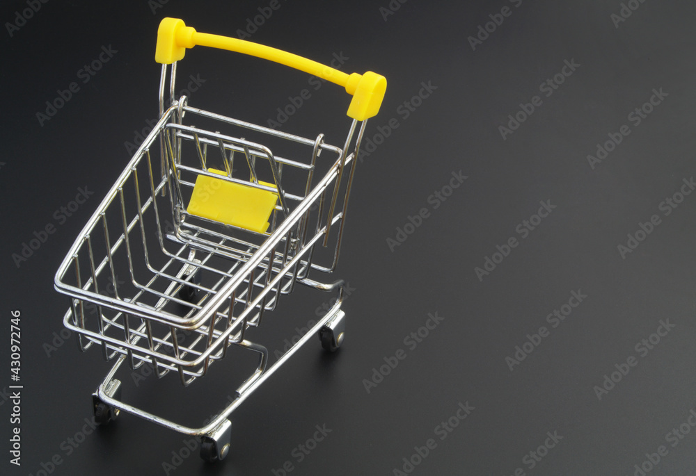 Shopping cart on black background with space for text, buy and sale concept