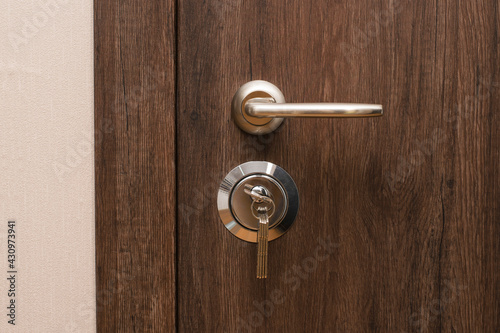 Door handle and lock with keys close-up. Closed modern entrance door in oak color.