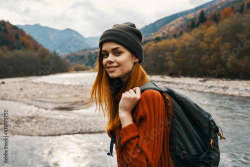 woman in a sweater cap with a backpack on her back mountain river in nature