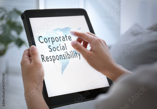 Corporate social responsibility concept. Woman with tablet indoors, closeup