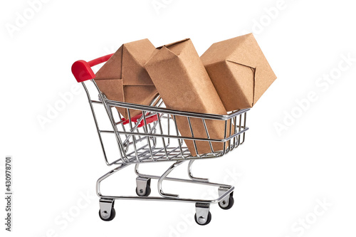 A small grocery cart. Toy shopping cart with boxes on white background. Festive concept. Copy space for text or design. Sale,discount, shopping and delivery concept. Consumer society trend. Isolated