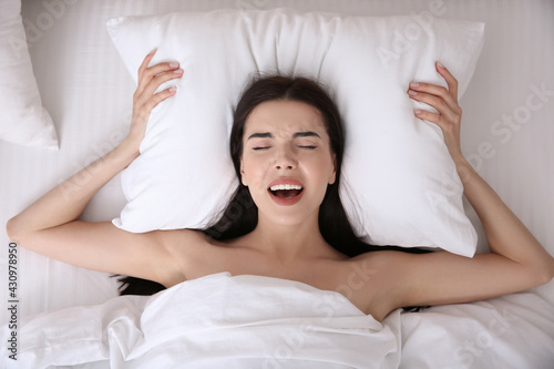Young woman having orgasm in bed, top view